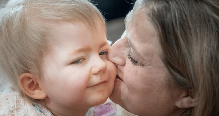 A mom kisses her smiling baby girl