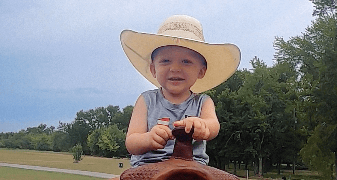A young boy in a cowboy hat enjoys riding a horse
