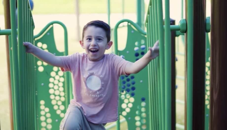 Video: a young boy is having a great time on a playground set